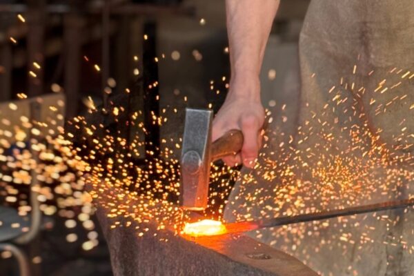 Man som slår med en slägga på glödande stål